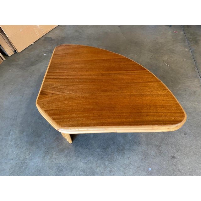 Vintage 1940s two-tier rattan side table featuring stylized three strand legs and beautiful half round mahogany tops....