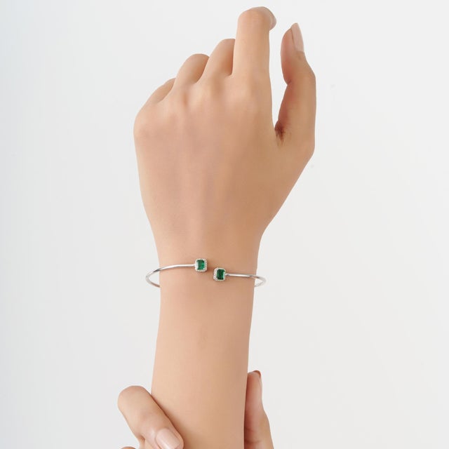 This Toi et Moi open cuff bangle is crafted in 925 sterling silver, featuring a 0.90-carat octagon-cut emerald paired with...