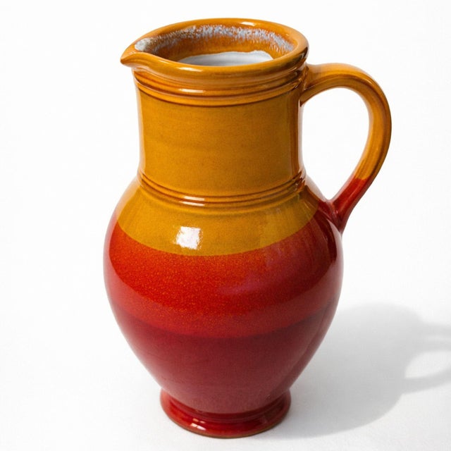 Striking vintage ceramic pitcher vase featuring a bold two-tone glaze in warm orange and deep red. Believed to be of...
