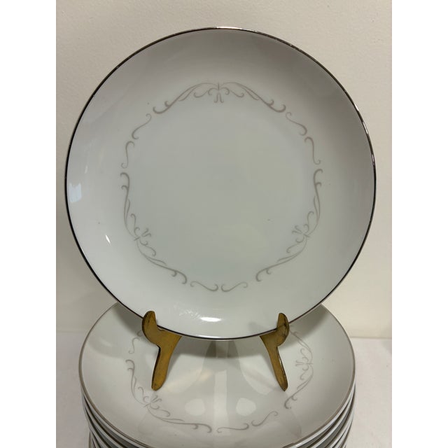 Description: A set of 12 Kimberly Fine China bread and butter plates in the "Trianon" pattern, featuring a delicate...