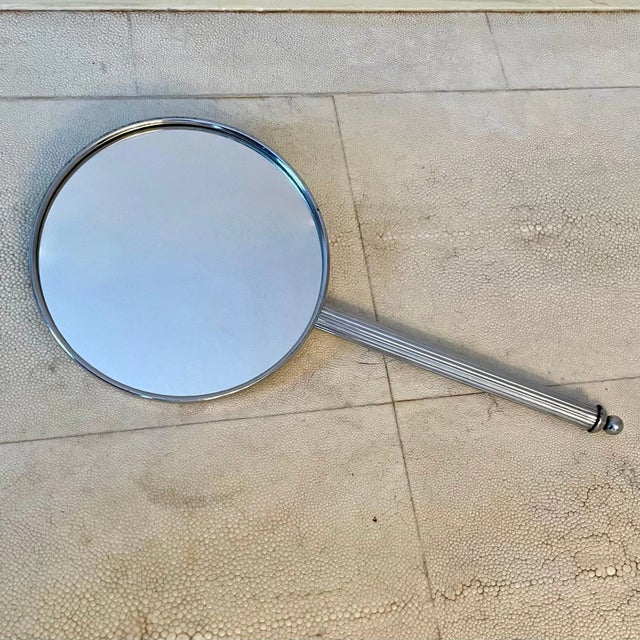 Silverplate hand mirror. Pinstripe detail on the handle gives way to a radial groove pattern on the back.