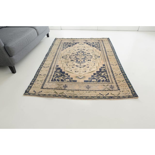 This is a vintage Turkish Oushak rug from the Mid 20th Century. The piece was hand-knotted.
