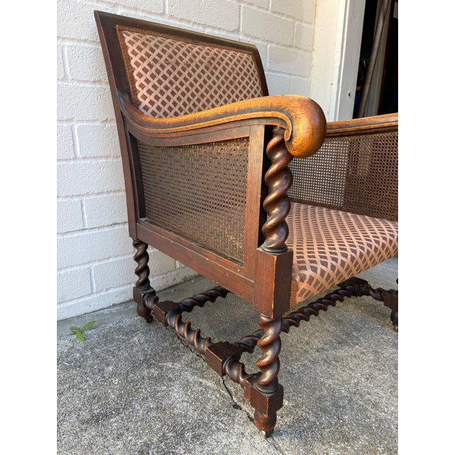 Antique oak Bergere armchair featuring barley twist legs, arms, and stretchers, with cane paneling sides and caster...