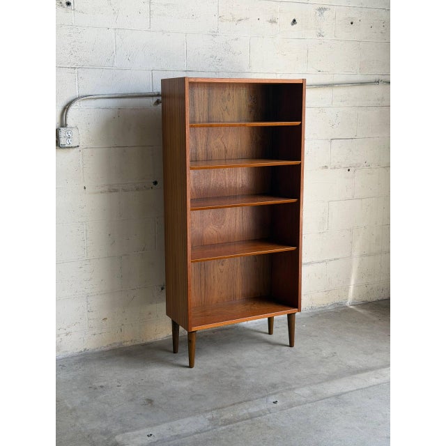 Vintage Danish modern bookcase in style of Poul Hundevad, crafted in beautifully grained teak and raised on elegant...