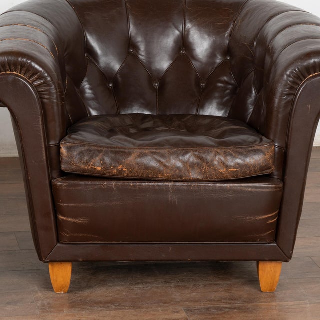 This pair of vintage leather club chairs are welcoming with barrel shaped arms and tufted backs with self covered buttons...