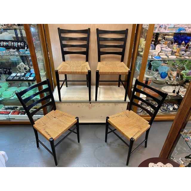 Set of four ladder-back dining chairs from 1960s Sweden, featuring black lacquered wood frames and hand-woven rope seats...