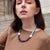 Handmade ceramic beads from Malta run the top, matte, porous, two shades of sky blue. Matte amethyst from Siberia takes...