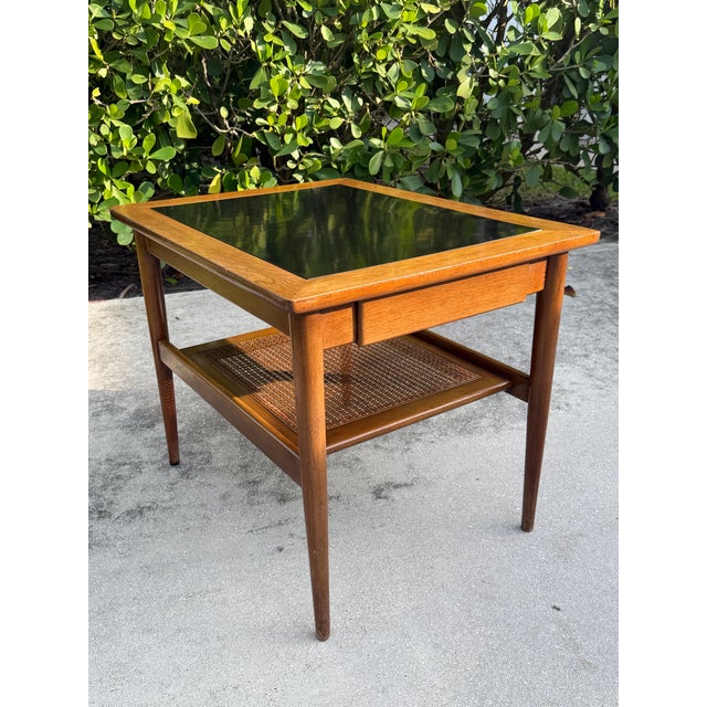 A handsome mid-century modern end table by American of Martinsville featuring a warm walnut frame, black mica inset top,...