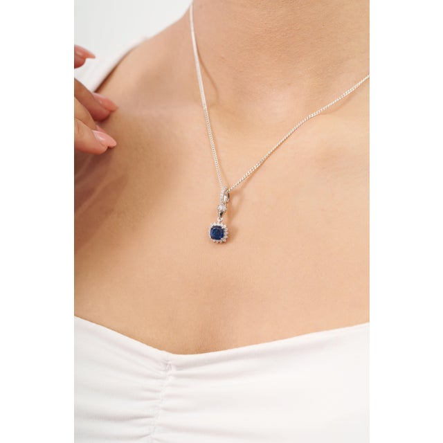 This halo enhancer pendant features a 1.14-carat cushion-cut deep blue sapphire, set in 14k white gold. The center stone...