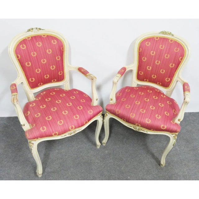 A pair of cream painted chairs with carved floral gold gilt accents, pink and gold upholstery
