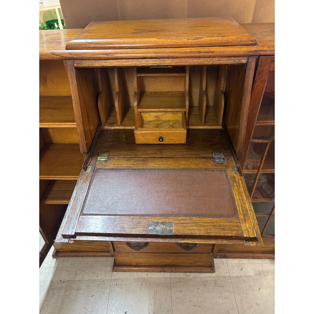 This Oak Art Deco Side By Side Bookcase / Front Drop Desk is an antique piece with a light tone finish, made of oak wood...