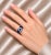 Exquisite 18K White Gold Hidalgo Ring featuring blue enamel, a genuine 6 mm × 4 mm sapphire center stone, and 12 brilliant...