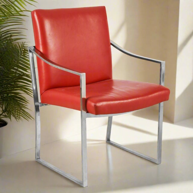 Sleek, chromed steel frame with down swept arms, sled base. Upholstered in a muted, orange red leather. 1970s original...