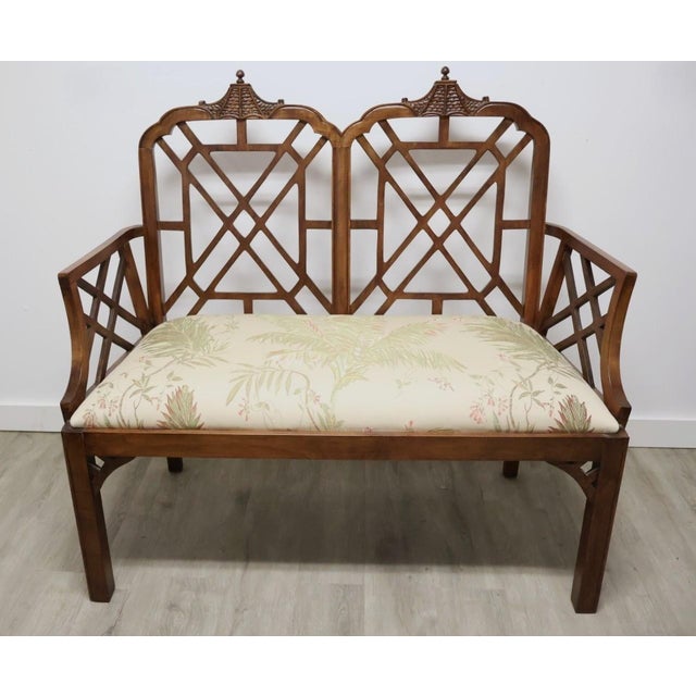 An elegant Chinese Chippendale-style settee featuring a distinctive double pagoda-form back with geometric fretwork...