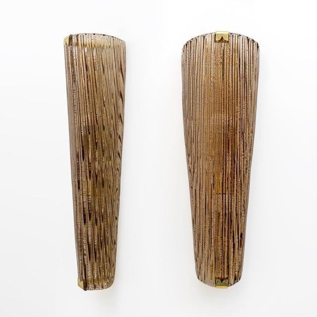 Pair of modern wall lamps with an elegant and luxurious design. The structure has an elongated and tapered shape in Murano...