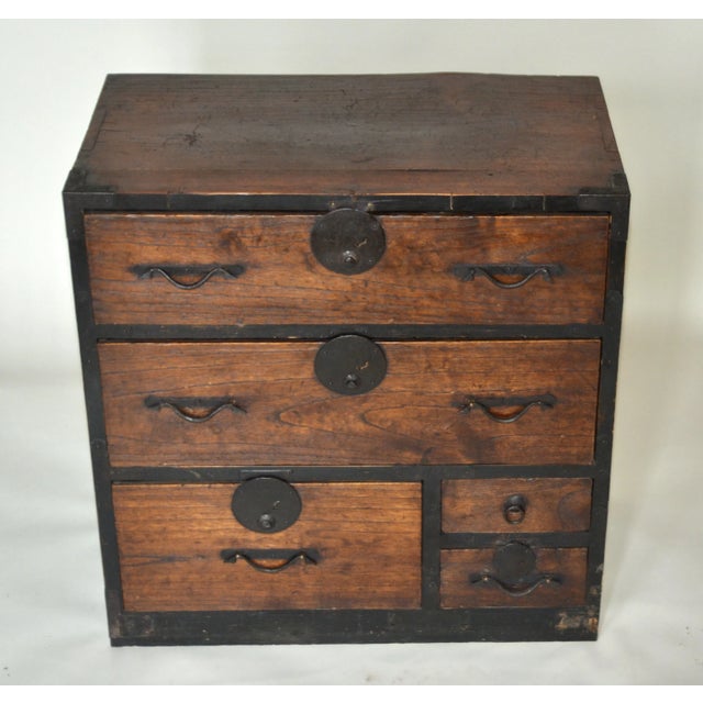 An antique Japanese tansu chest, original hand forged iron hardware and wiped lacquer finish. Five drawers of varying...
