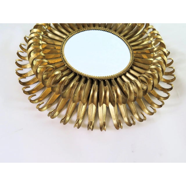 This heavy brass wrought iron Sunburst mirror is in the manner of the Hollywood Regency style. What makes it unique from...