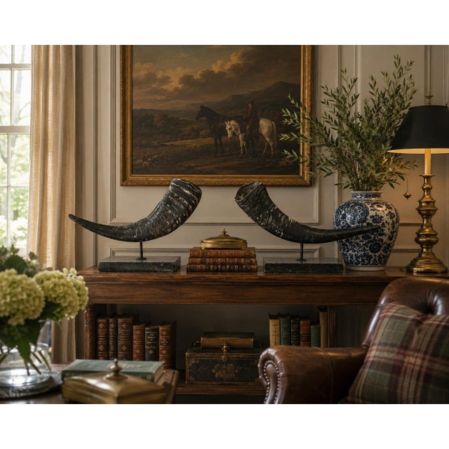 A sophisticated pair of vintage faux ram horns mounted on substantial black marble plinths, offering the timeless sporting...