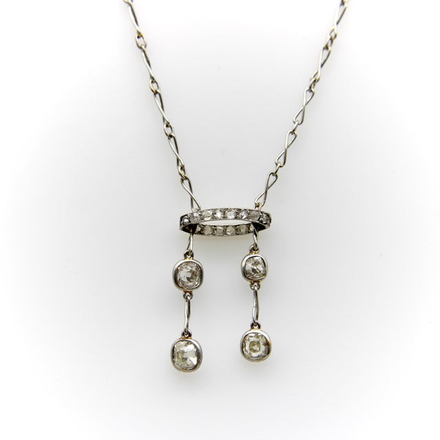 This platinum Edwardian negligee necklace features four Old Mine Cut diamonds and a diamond encrusted halo element. The...