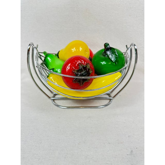 Eight pieces of glass fruit in a metal hammock type bowl. A colorful addition to the kitchen or dining room. This is a...