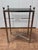 A slim side table in the Directoire style, after Maison Jansen. The frame is polished nickel, with column legs topped by...