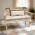 A charming vintage French Country style carved wood settee featuring a distressed cream painted finish, custom toile...