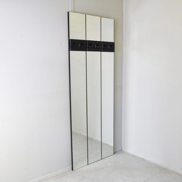 Wall-mounted mirror-and-coat-rack panels of this kind belong to a design language distinctly Italian of the late 1970s and...
