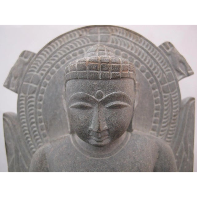 Hand-carved stone sculpture of a seated Buddha performing the Dharmachakra Mudra (the gesture of teaching or turning the...