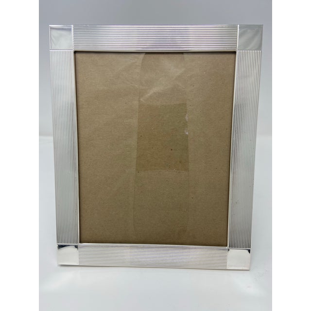 Large 8x10” silverplate reeded picture frame with block corners . Made in England . Excellent condition. Overall size 10x12”.