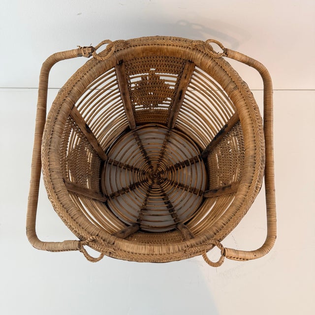 A beautifully textured vintage rattan basket featuring double swing handles and intricate geometric woven panels. The...