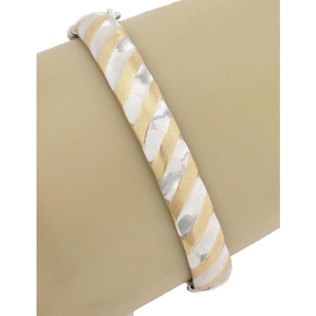 This lovely bangle bracelet is crafted in hollow 14k yellow and white gold and features a beautiful slanted stripe pattern...