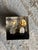 A whimsical 2" square lucite cube with bright floating pennies, all dated 1972, mounted on a black base with tiny bun...