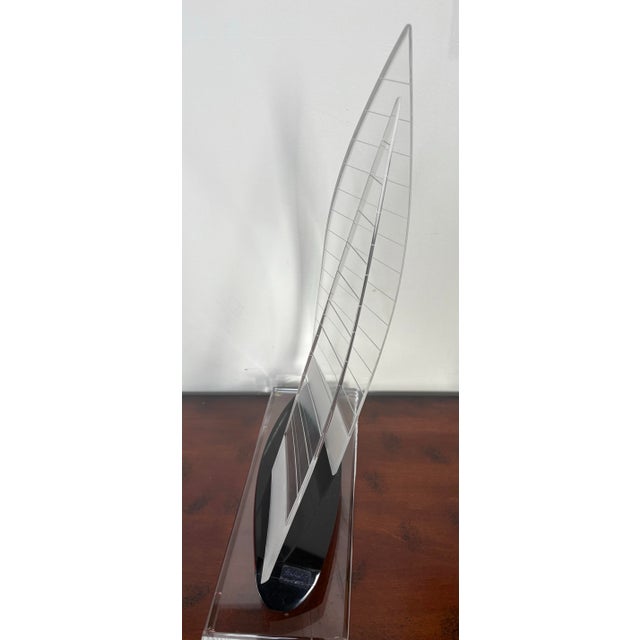 A sculptural postmodern sailboat rendered in clear etched acrylic with an asymmetrical twin-sail design. The black hull...