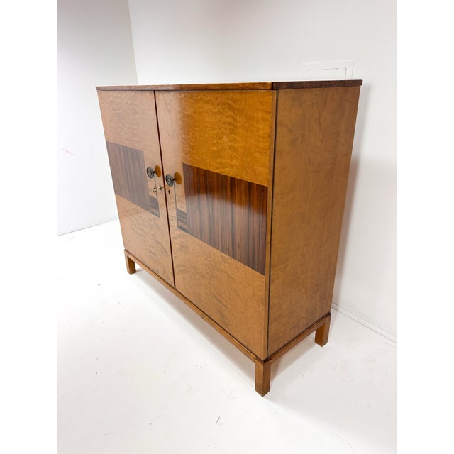 1930's Swedish Art Deco Cabinet. Birch wood cabinet with rosewood inlays. Two large doors conceal interior adjustable...