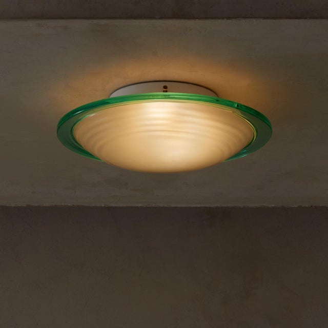 A 1960s Murano glass flush mount featuring a gently ribbed frosted glass shade, encased within a bold turquoise glass...