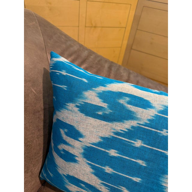 Horizontal white forms ripple across a sky blue silk ground from edge to edge, the resist-dyed threads creating a...