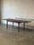 This exceptional expandable dining table features a clean rectangular top supported by slender tapered legs. Two...