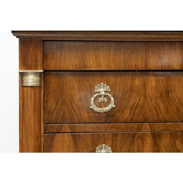 This is an elegant French Empire-style commode crafted in richly figured flame mahogany, showcasing the bold architectural...