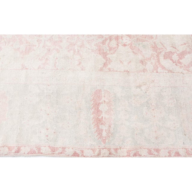 An Indian Agra rug, the dusty rose field with an allover design of palmettes, flowering vines and cloudbands within a...