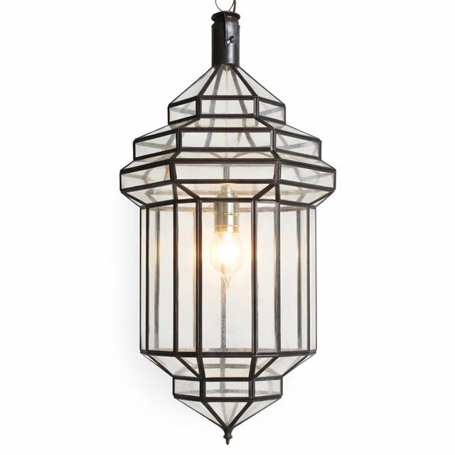 Striking Moroccan pendant lantern hand crafted from clear glass panels set within a dark bronze finish metal frame....