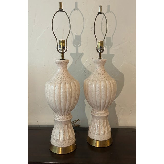 This pair of 1960's Hollywood Regency style table lamps are exquisite down to the last detail. The bases are ivory colored...
