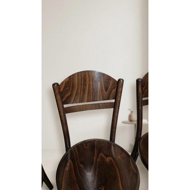 A classic set of four czechoslovak wooden dining chairs manufactured by ton, featuring gently curved backrests, round...