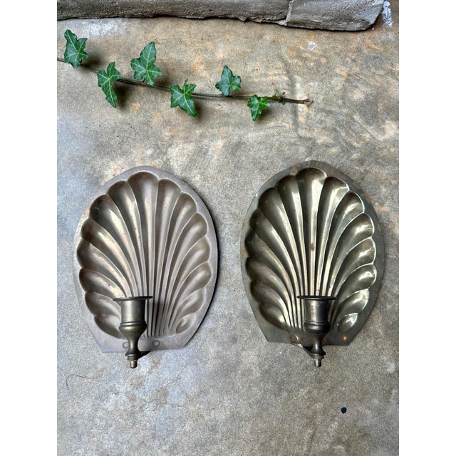 Striking pair of vintage wall sconces featuring sculptural scallop shell backplates with single candle cups. The fluted...