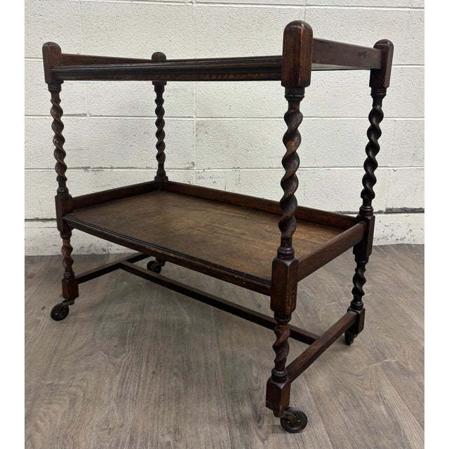 This is a beautiful antique English oak barley twist trolley, tea cart, or dumbwaiter. It features fascinating barley...