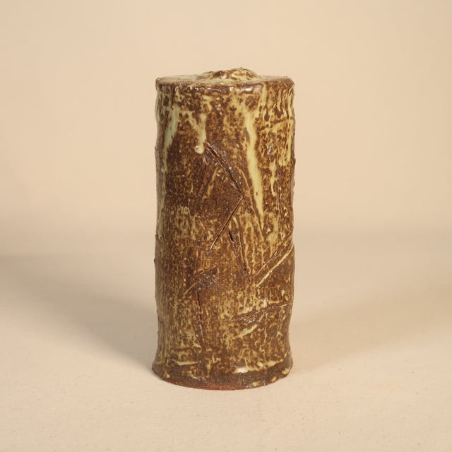 This tall, cylindrical studio pottery bud vase is a striking example of hand-formed ceramic design. Its organic, tree-...