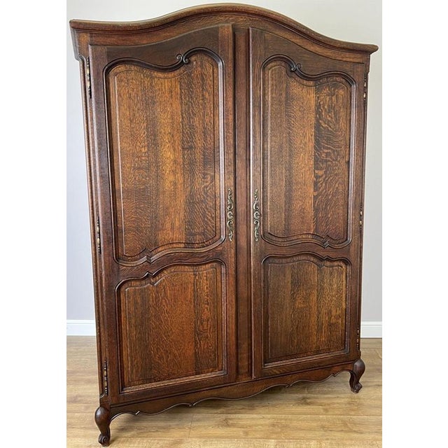 A handsome Antique French Louis wardrobe crafted in oak, featuring a rich warm finish, beautifully shaped panelled doors,...