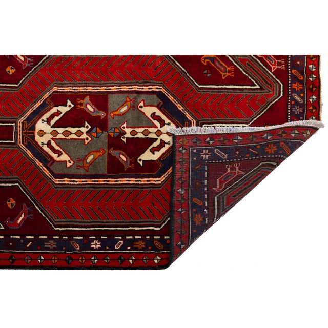Elevate your interior with this striking hand-knotted Caucasian Kazak wool runner. Characterized by its vibrant crimson...