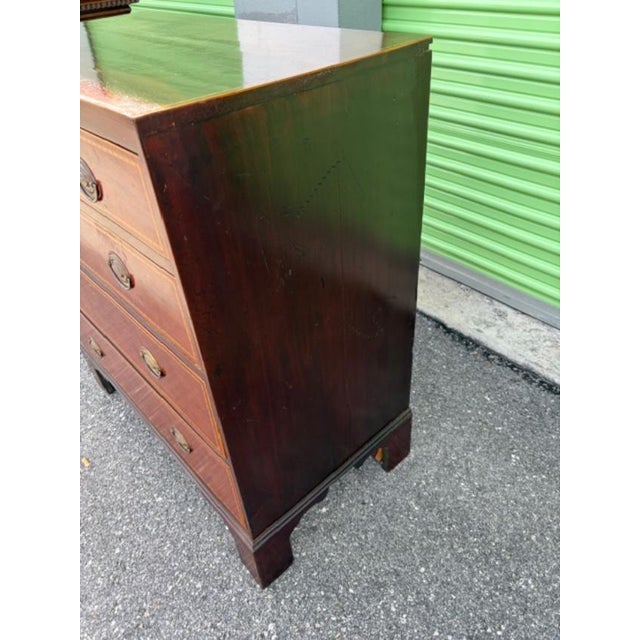 This English antique mahogany chest of drawers features a classic design with satinwood inlay and brass handle finish,...