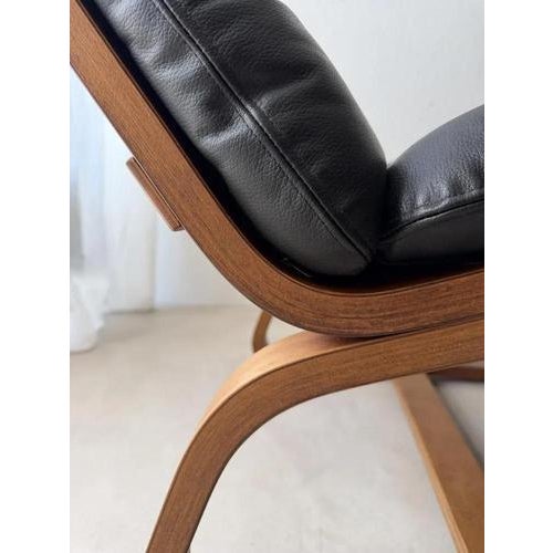 Mid-century armchair from the 1970s, constructed from carefully curved plywood and upholstered in supple black leather....