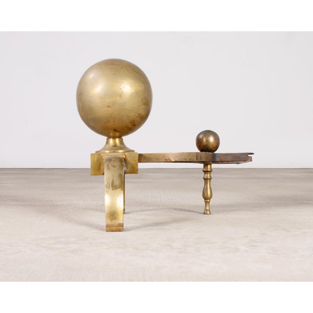 Handsome pair of English patinated brass andirons featuring large spherical cannonball finials. Made in the grand Regency...